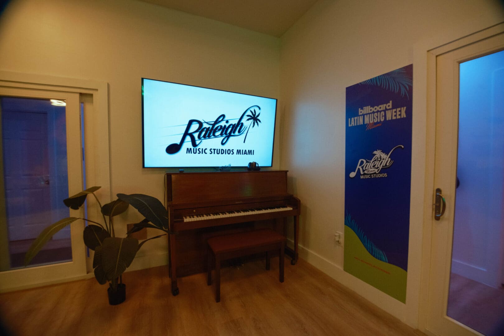 A piano in the corner of a room with a large screen.