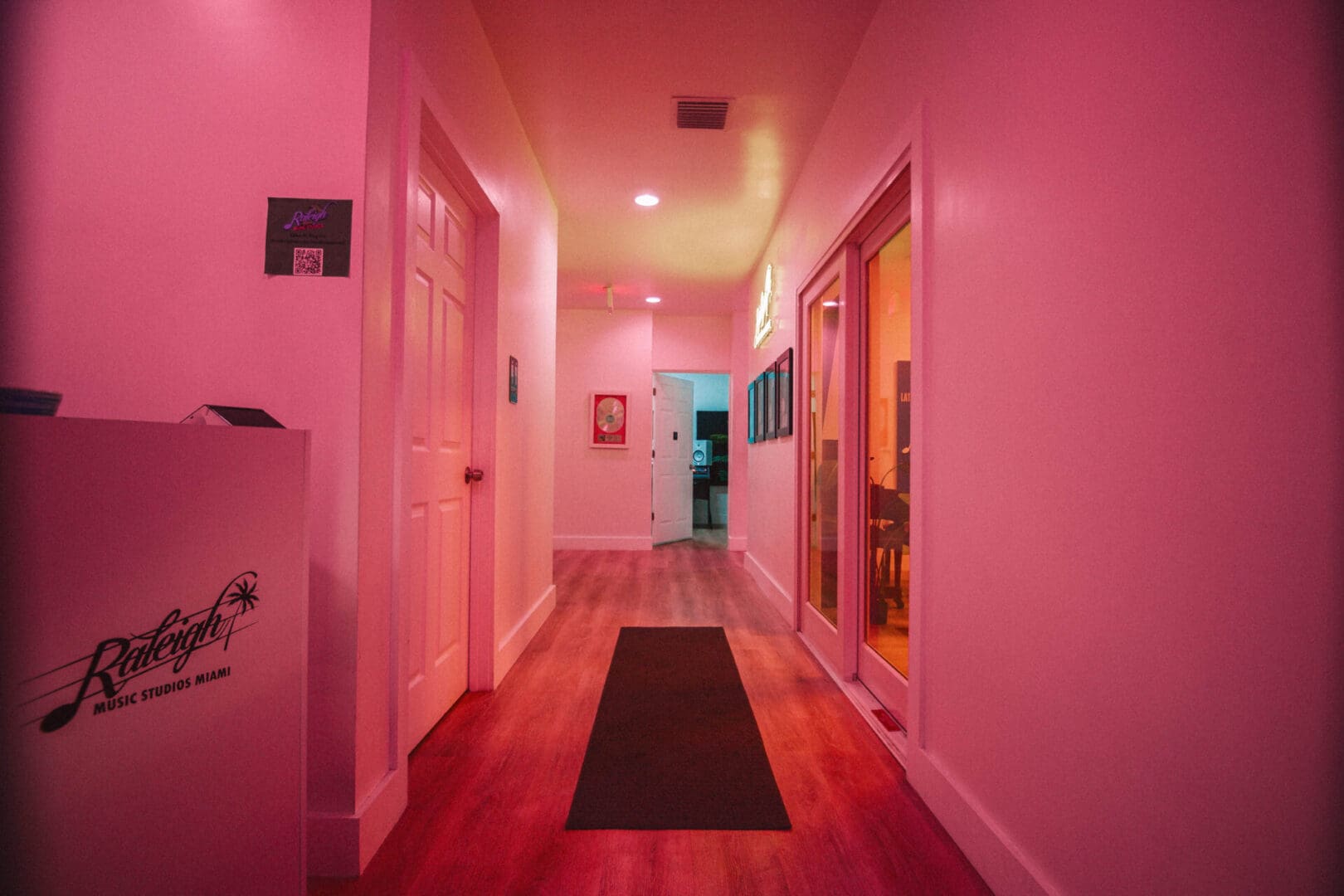 A hallway with pink walls and wooden floors.