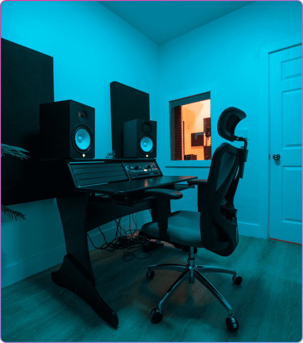 Purple music studio with mixing desk and speakers.