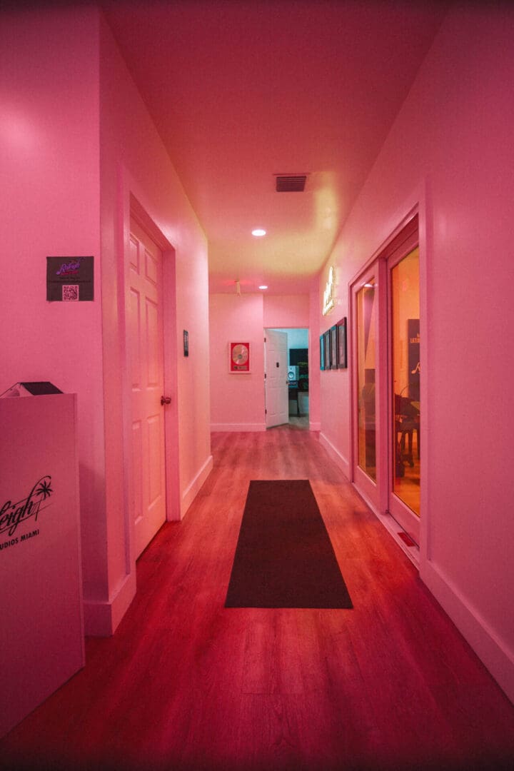 A hallway with pink walls and wooden floors.