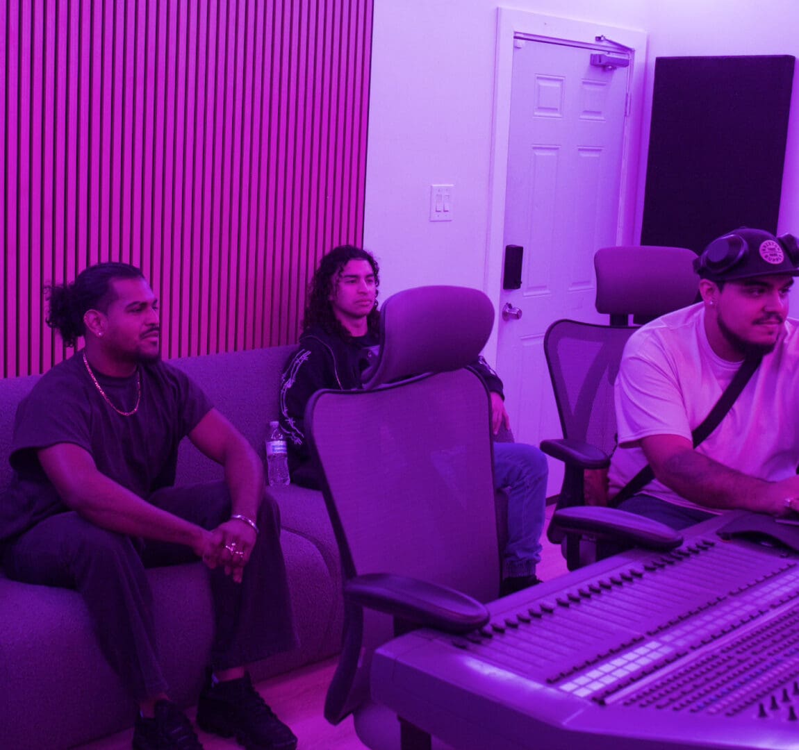 Three people sitting on a couch in front of a piano.