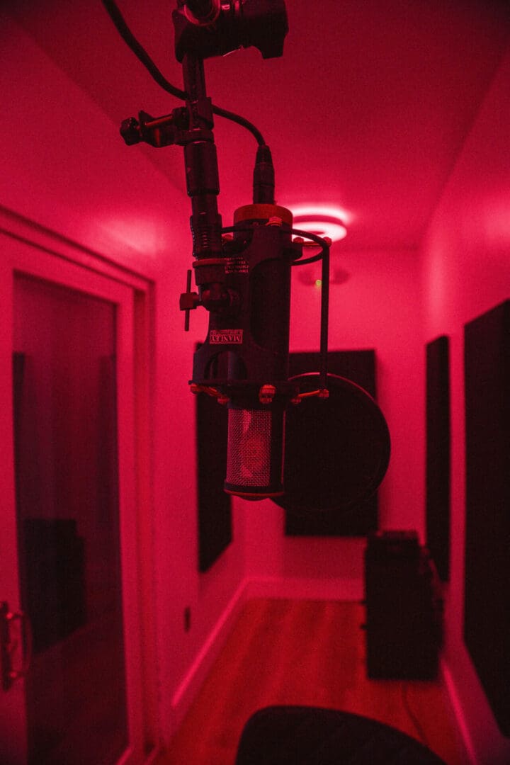 A hallway with red lights and a black door.