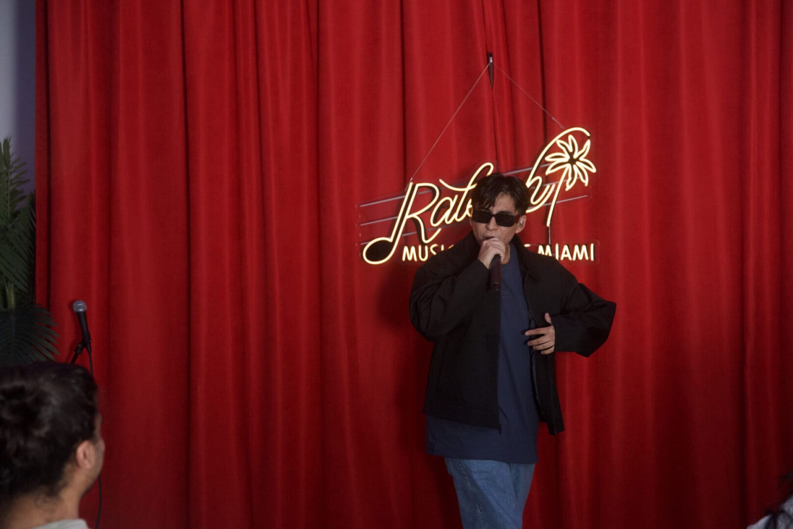 A person standing in front of a red curtain.