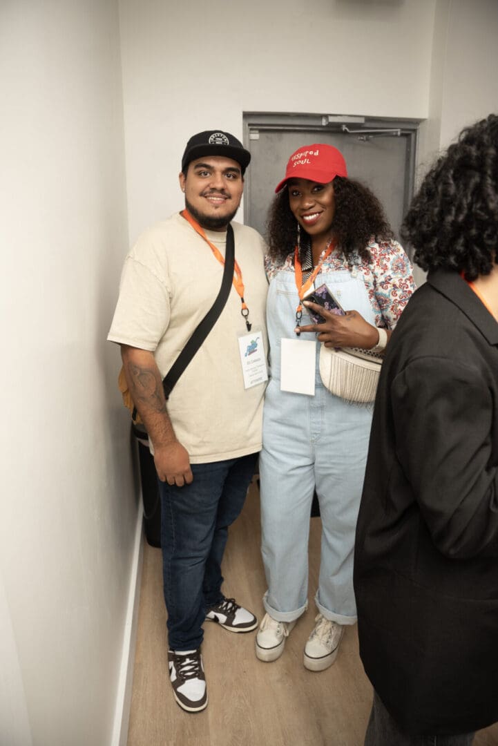 Two people standing in a hallway with one holding a cell phone.