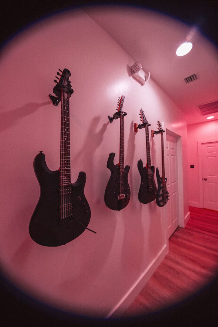 A room with four guitars hanging on the wall.