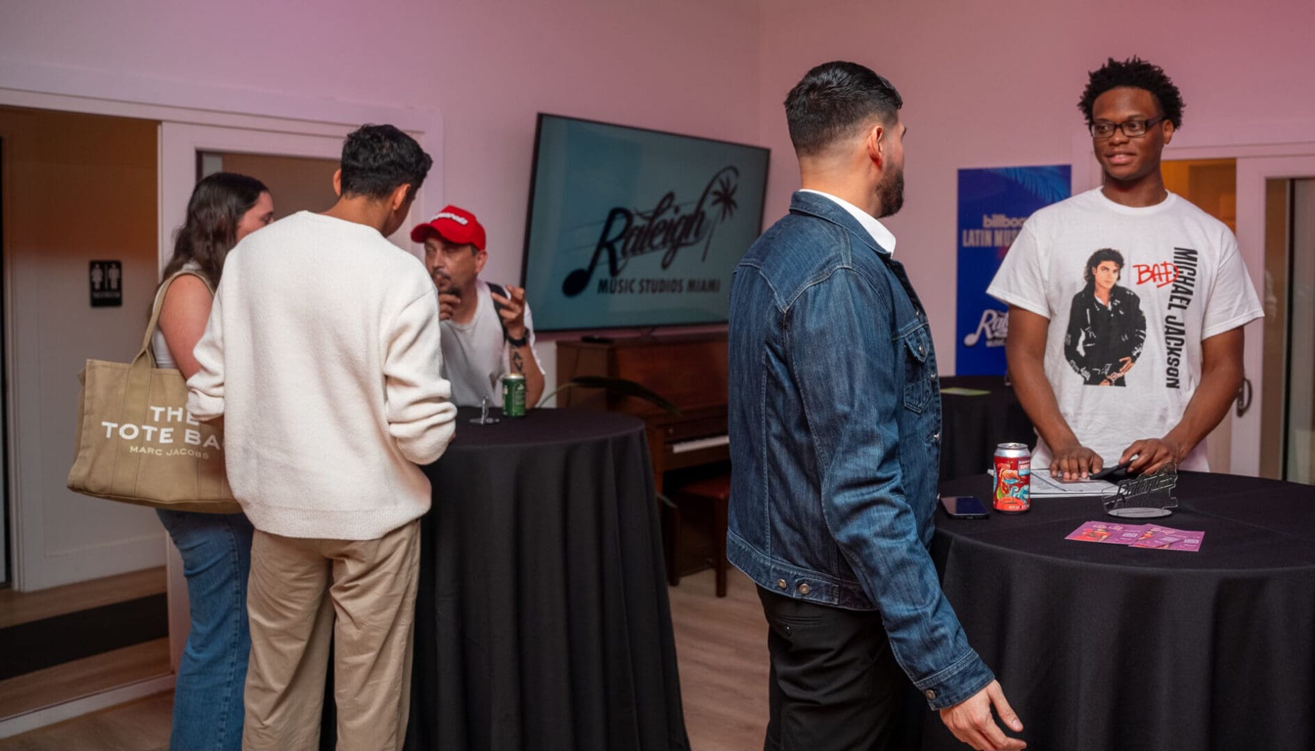 A group of people standing around tables with drinks.